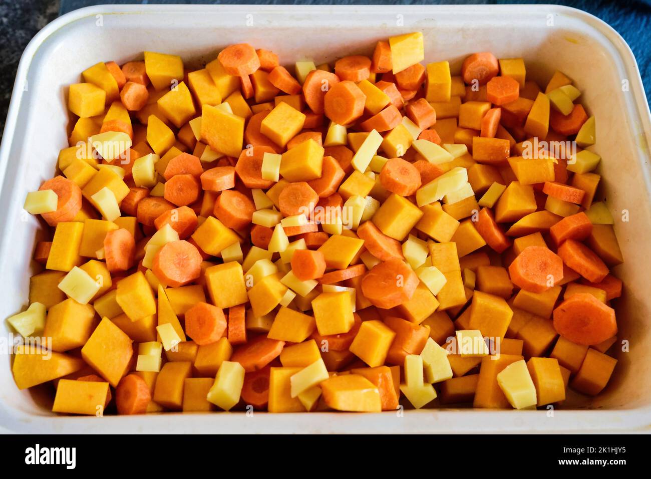 chopped carrots, potatoes and pumpkin in a baking dish Stock Photo