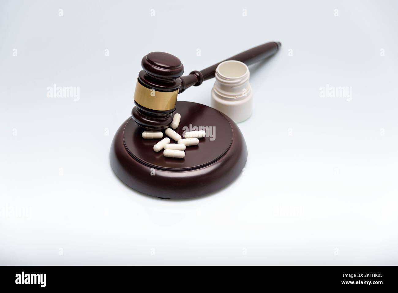 Medicine and law. Pills capsules and judge gavel isolated on white background. Stock Photo