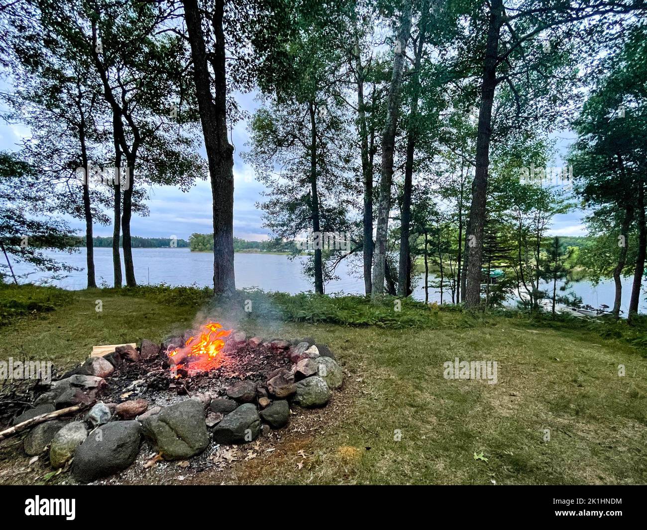 Campfire next to a calm lake in the summer, horizontal Stock Photo