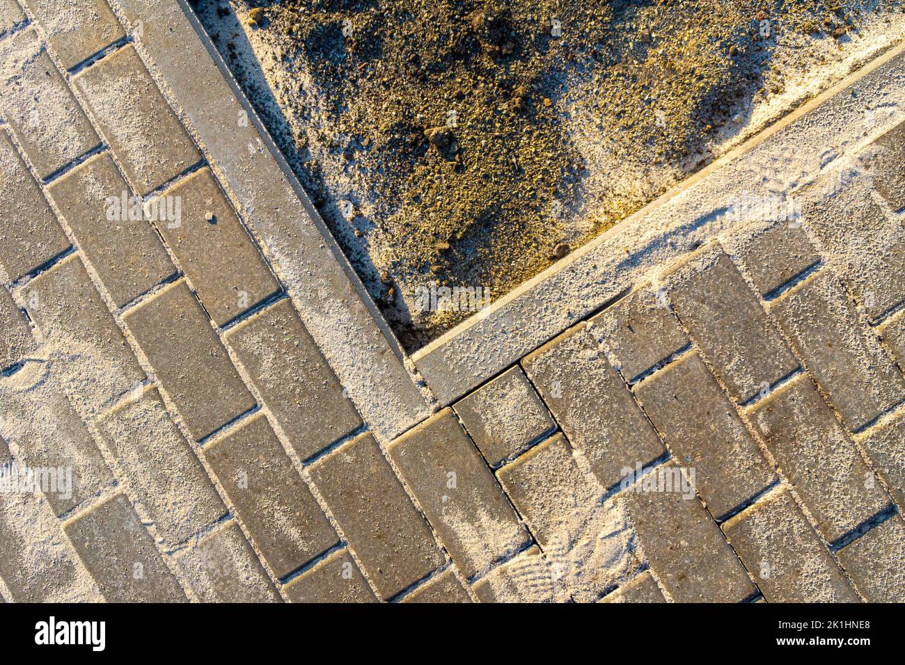 construction work during landscaping, the inner corner of the footpath enveloping the lawn, the sand filling the tile joints fell on the black earth f Stock Photo