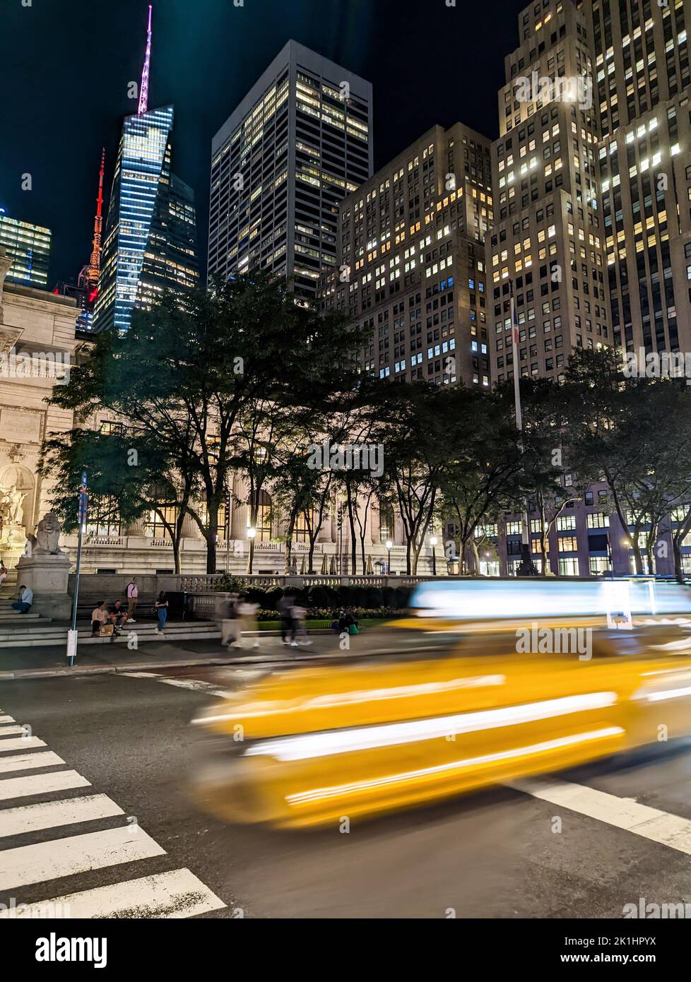 Blurred yellow taxi driving down the street in New York City at night ...
