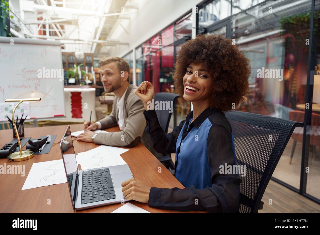 Smiling african businesswoman sitting on his workplace in modern office ...