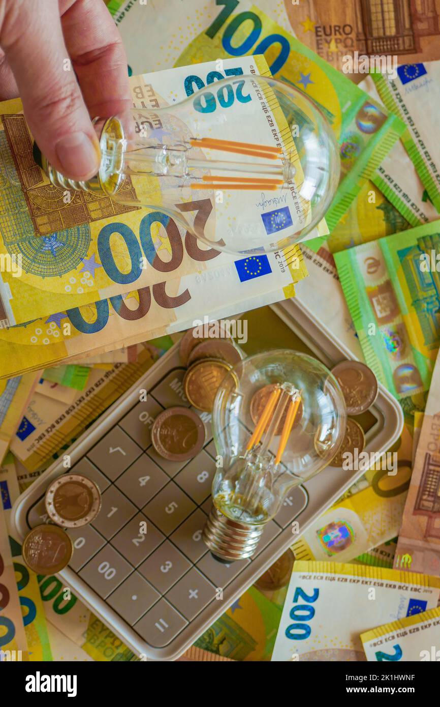 Paying electricity bills in Europe.Electric light bulb on euro bills background. Rising electricity prices. Energy production crisis in European Stock Photo