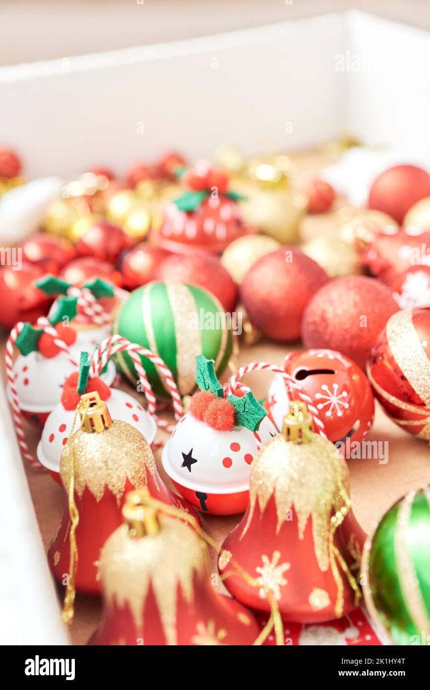 Box of mixed Christmas tree ornaments, balls and bells in the classic traditional colors of red, green, white and gold. Stock Photo