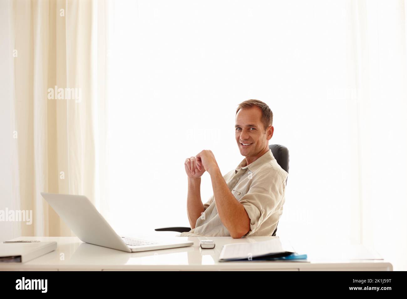 Comfort meets sophistication in this office. Mature businessman smiling confidently while working in an office. Stock Photo
