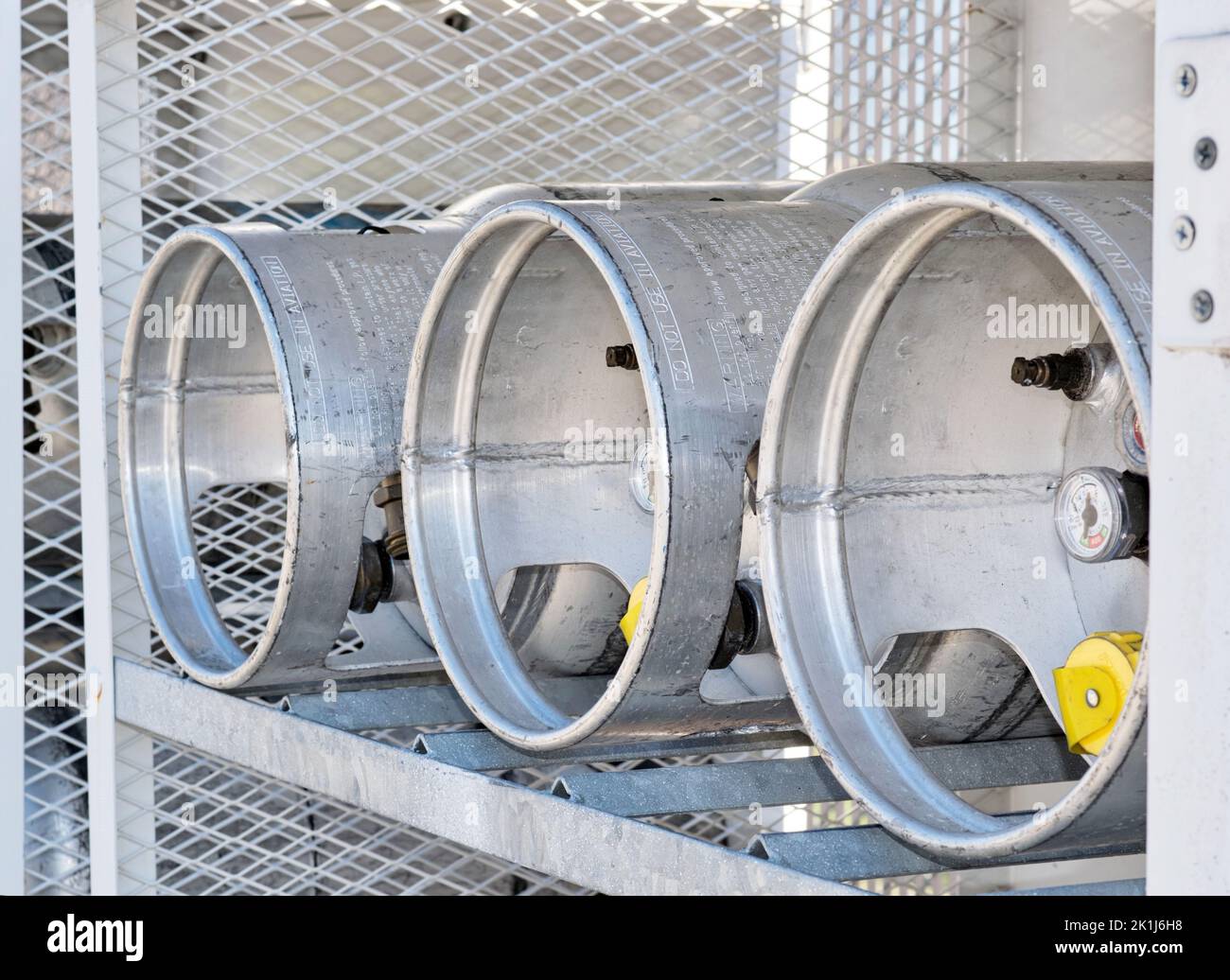 Houston, Texas USA 09-18-2022: Three Liquid Petroleum gas cylinders stored horizontally in a metal safety cage, eye level angle view with door open. Stock Photo