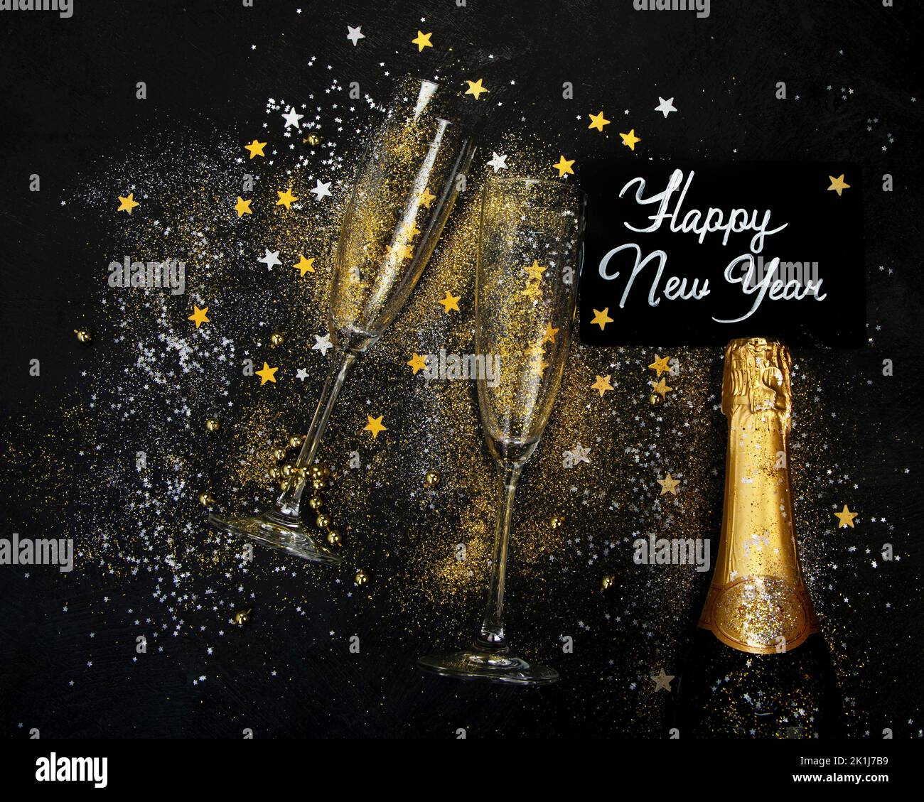 Glass of champagne and bottle on dark background. Traditional festive time drinks. Top view, copy space Stock Photo