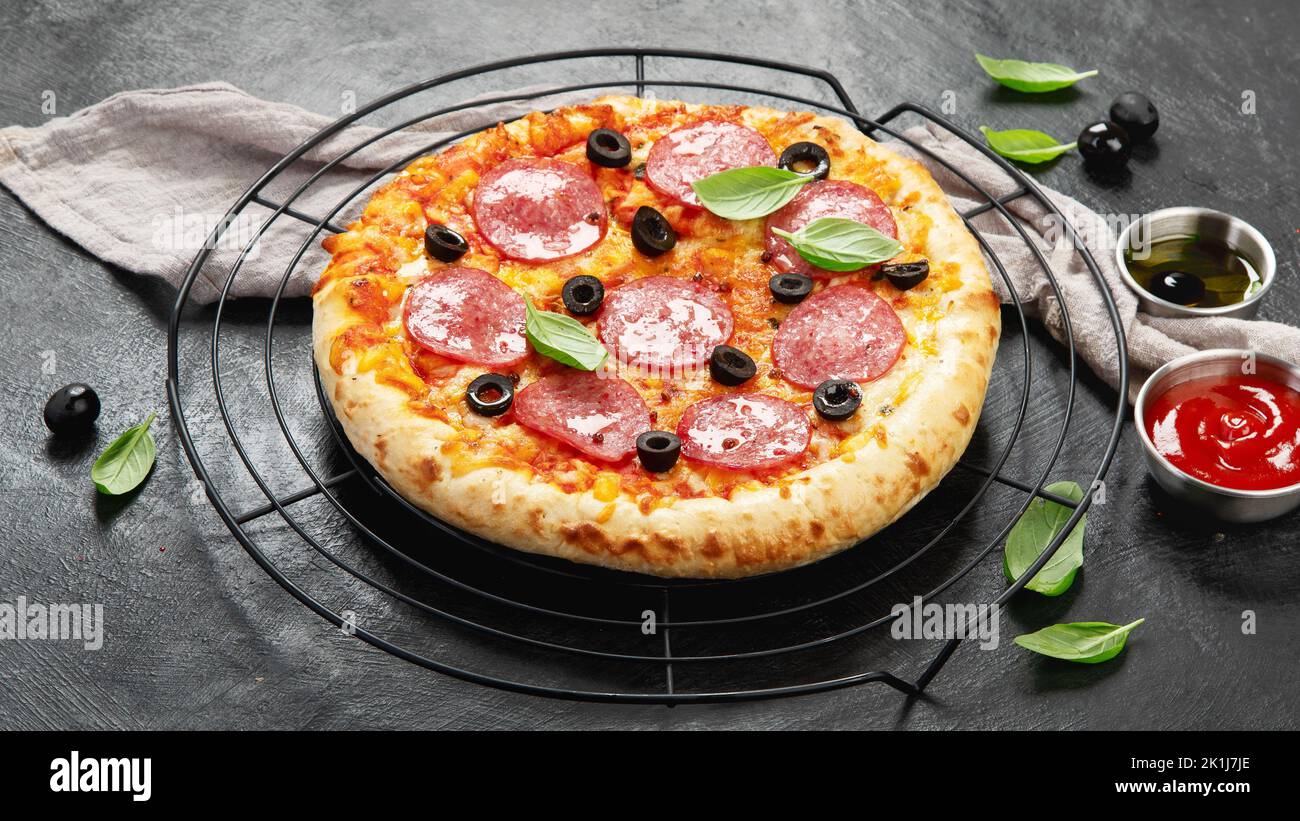 Freshly baked pepperoni pizza on dark background. Tasty homemade food concept. Stock Photo