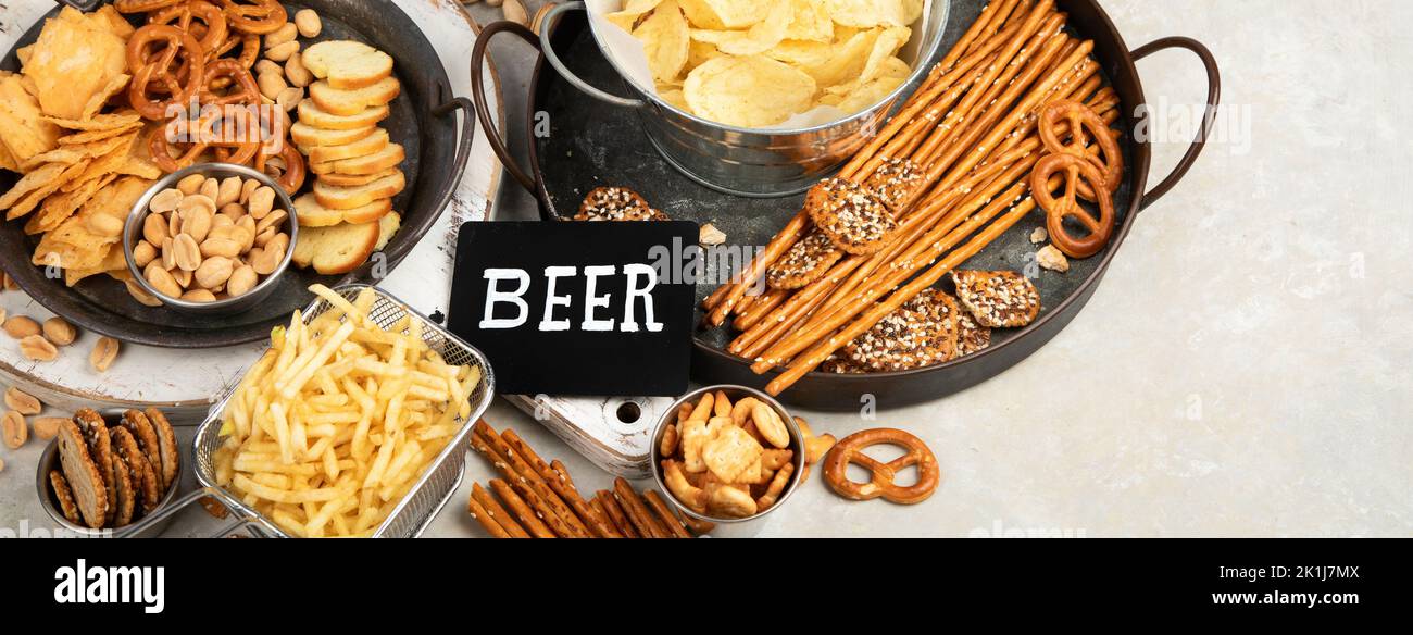 Assortment of beer and salty snacks on light background. Party food concept. copy space, panorama Stock Photo