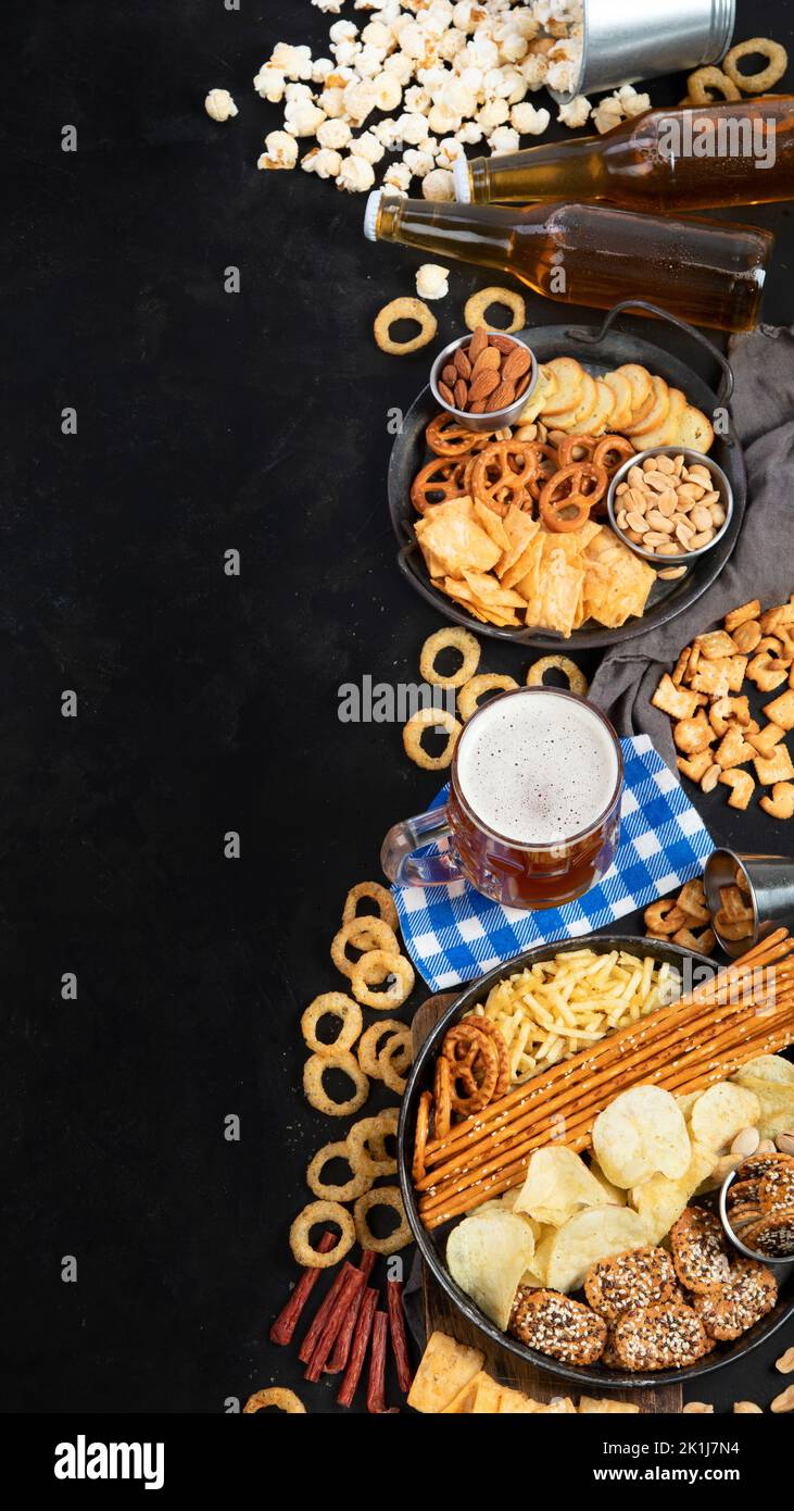 Assortment of beer and salty snacks on dark background. Party food concept. Top view, copy space Stock Photo