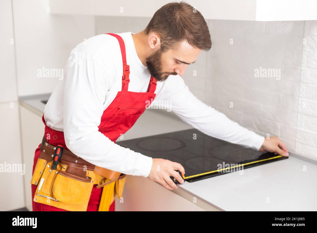 craftsman installs hob in kitchen. Household Appliance Installation Services Concept Stock Photo
