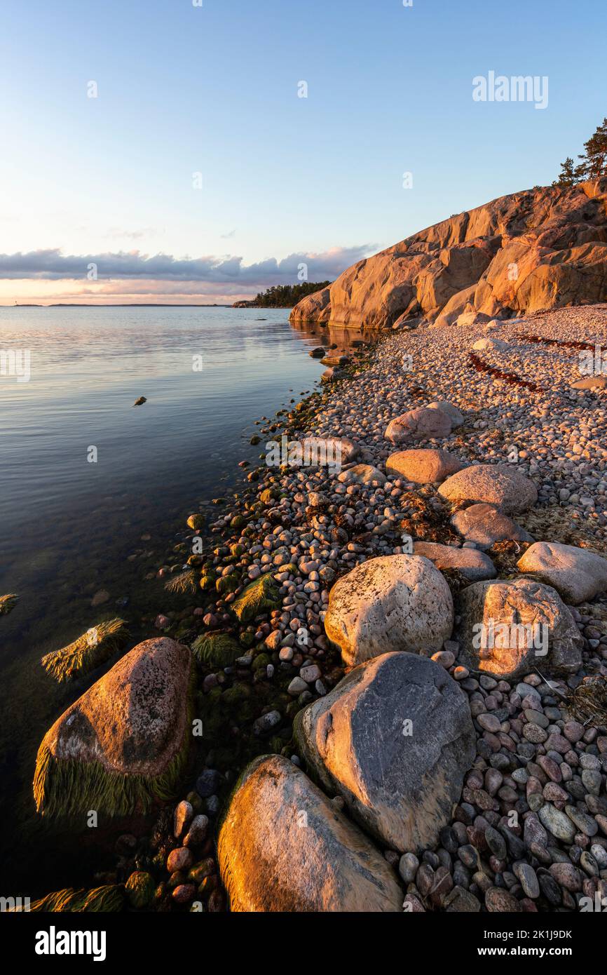 Beautiful view of rocky pebble beach, cliff and the Baltic Sea in Hanko, Finland, at sunset in the summer. Stock Photo