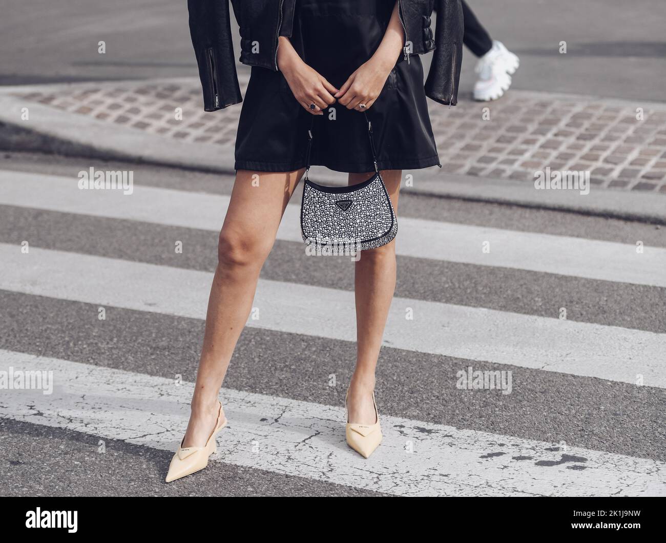 Milan, Italy - February, 24: Street style, woman wearing Prada outfit: black shiny leather oversized biker jacket, black short dress, a black Cleo han Stock Photo
