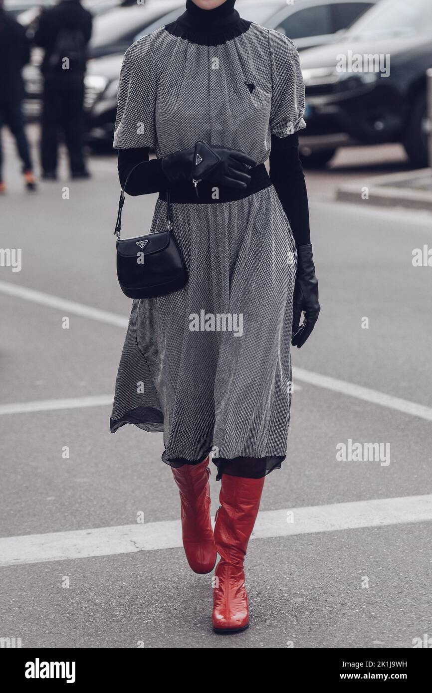 Milan, Italy - February, 24: Street style, woman wearing grey dress, black gloves, bag, red boots. Stock Photo