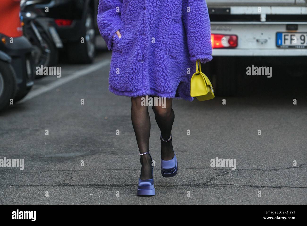 Milan, Italy - February, 24: Street style, woman wearing a furry purple coat, yellow bag and purple sandals.. Stock Photo