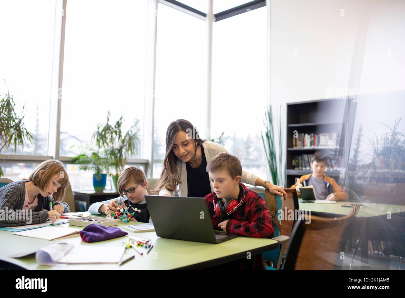 Junior high teacher helping student with Down Syndrome at laptop in