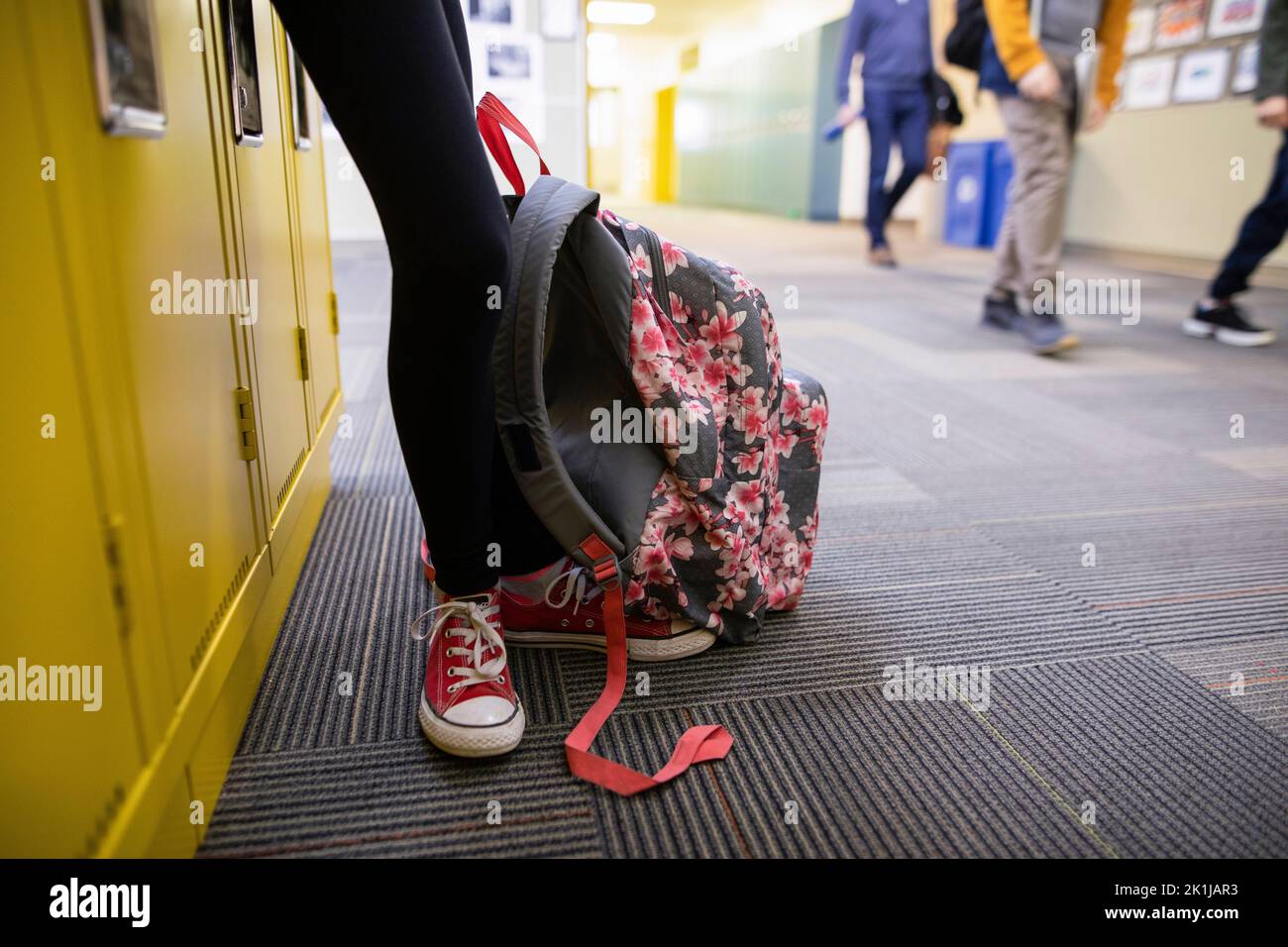Junior high girl student with backpack leaning against lockers in