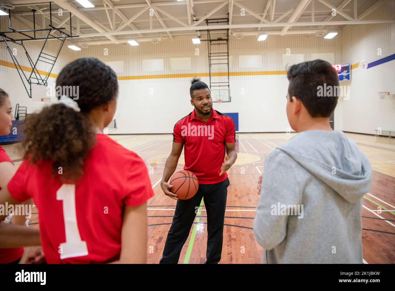 Junior high basketball coach coaching students in gym Stock Photo Alamy