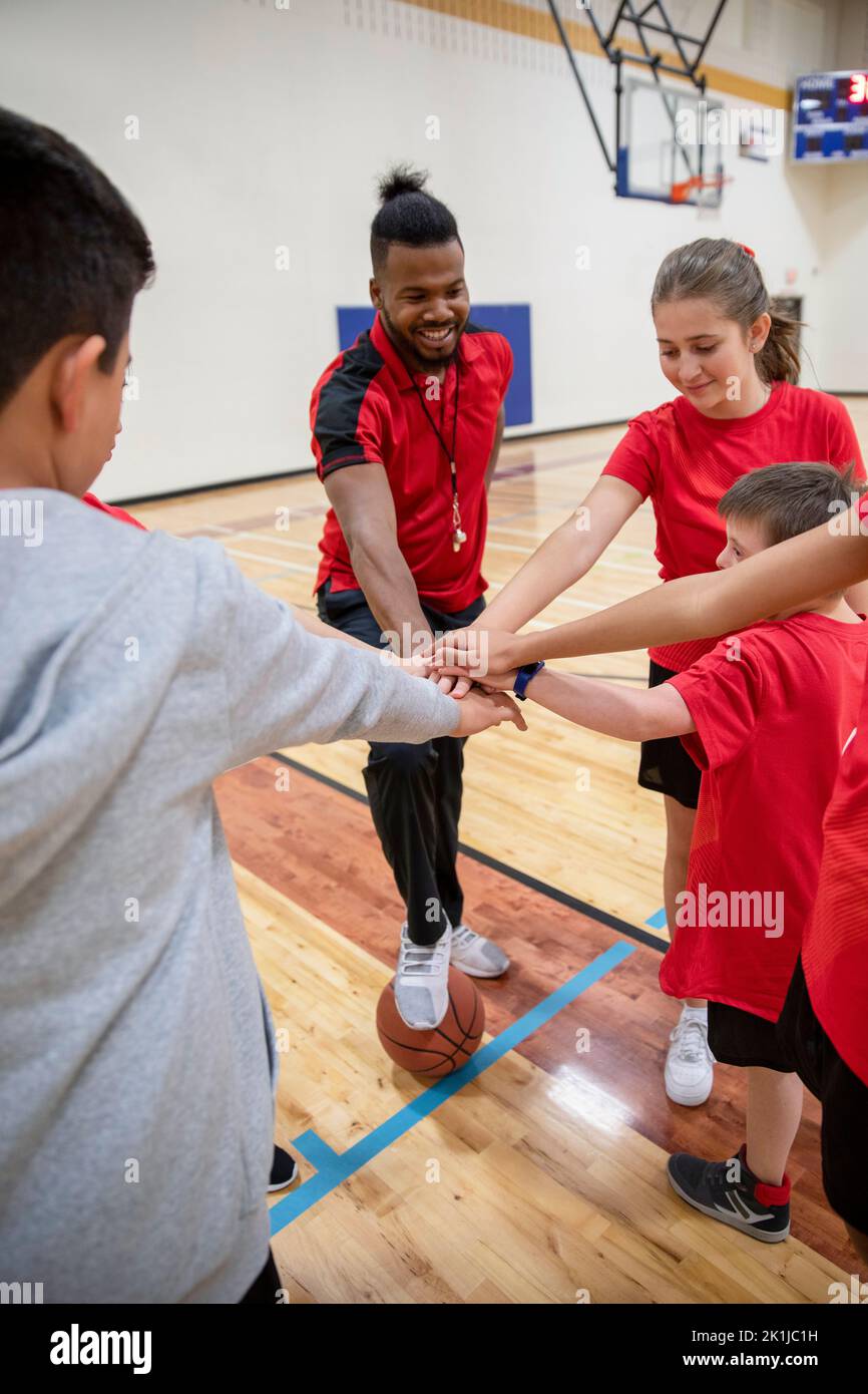 Junior high gym teacher and students joining hands in huddle in