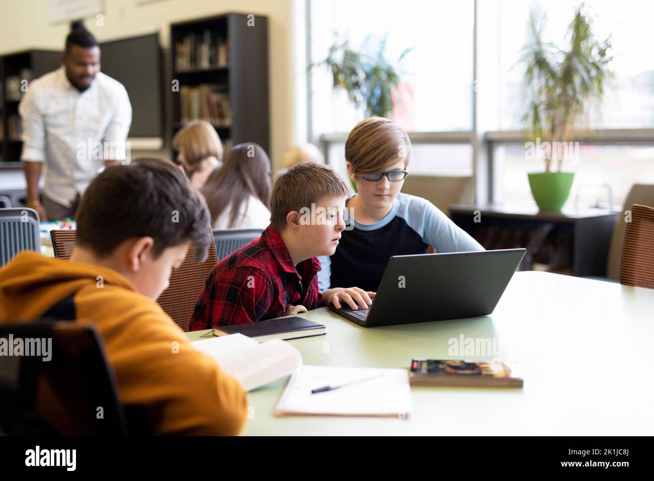 Junior high student with Down Syndrome using laptop with classmate in