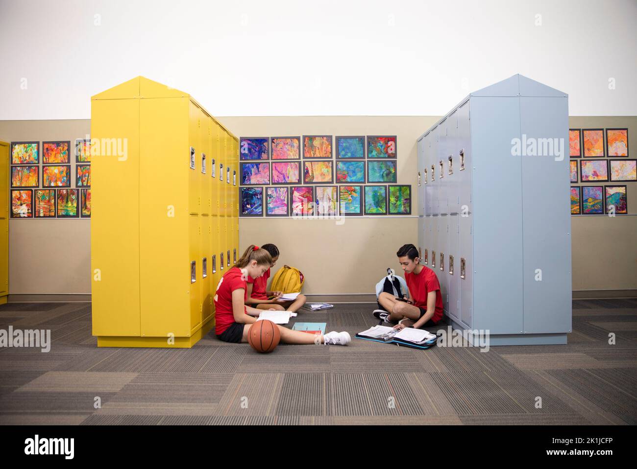 Junior high basketball player students studying at lockers Stock Photo