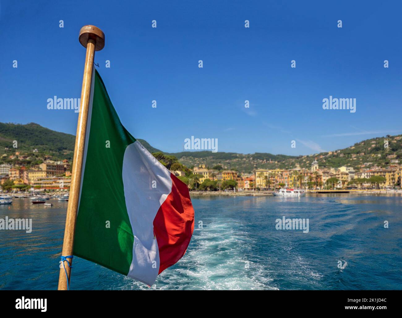 Italian Flag on rear of boat with the Mediterranean coast in the background - for use as a background Stock Photo