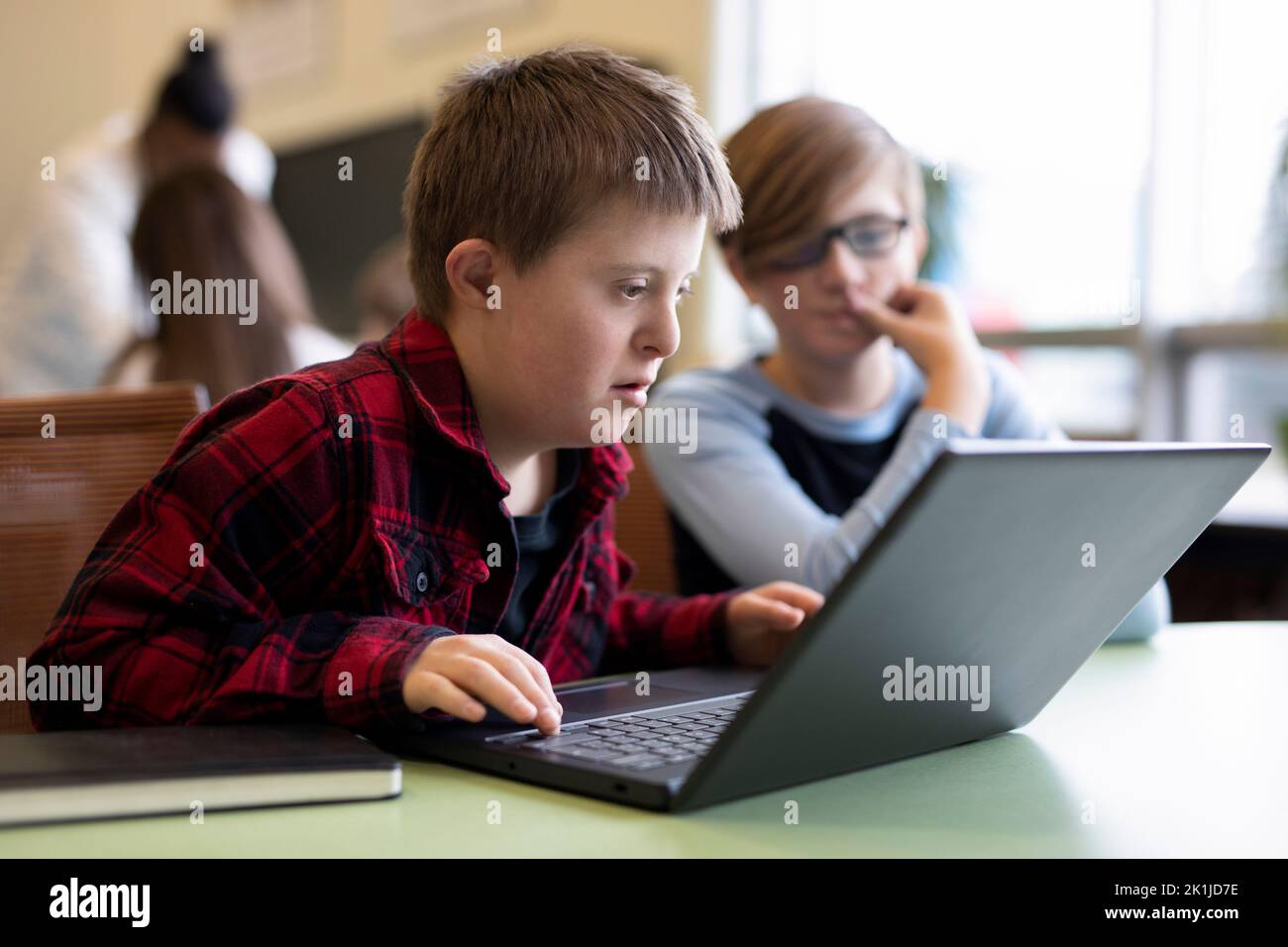 Focused junior high boy with Down Syndrome using laptop in classroom