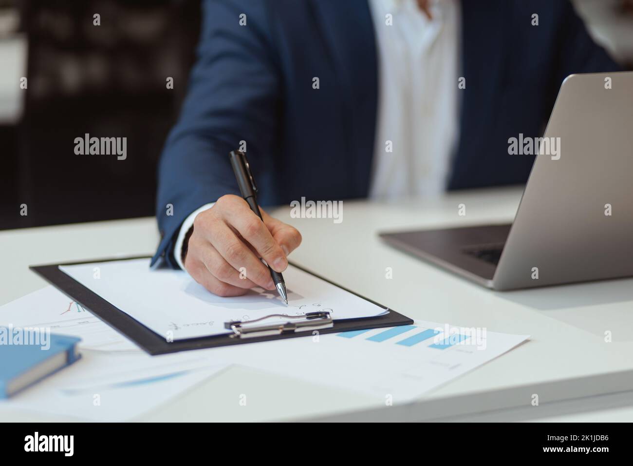 Close up of businessman hand which taking notes while working on laptop in office Stock Photo