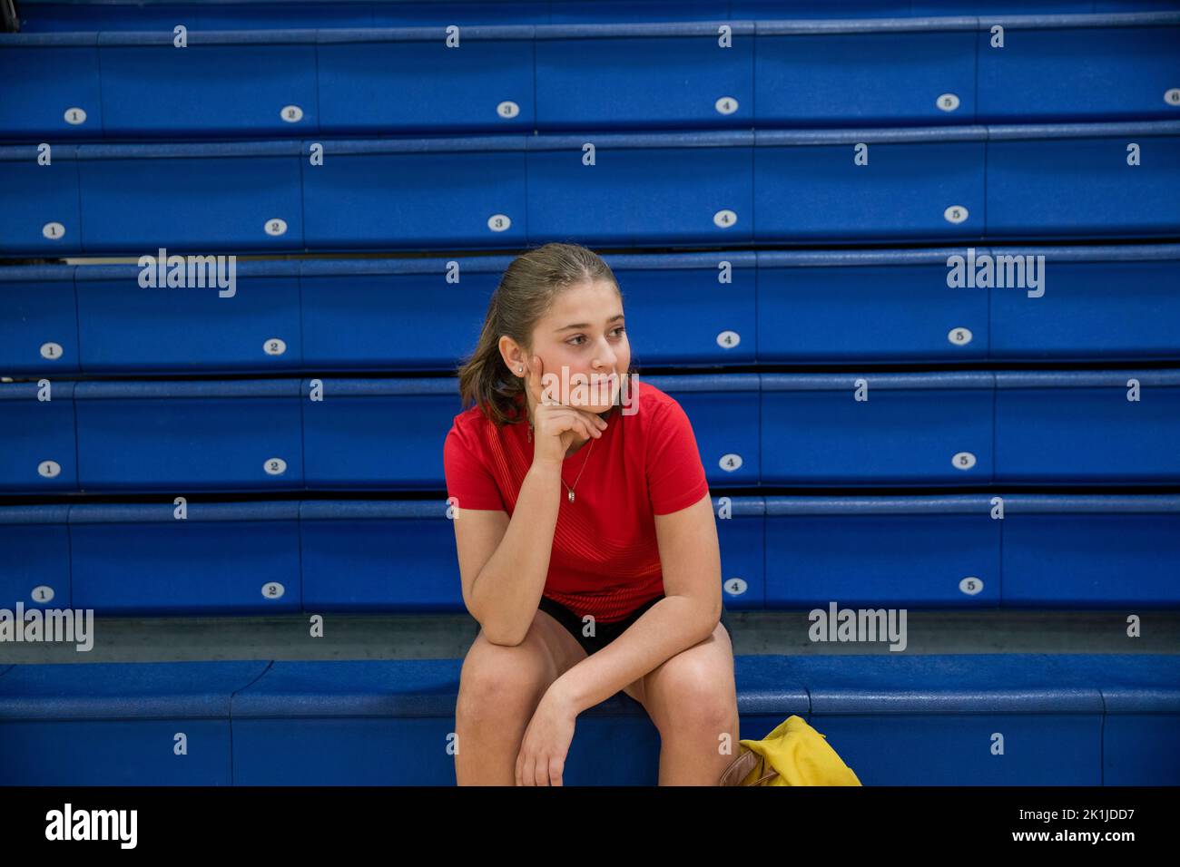 Junior high girl student sitting on bleachers in gymnasium Stock Photo