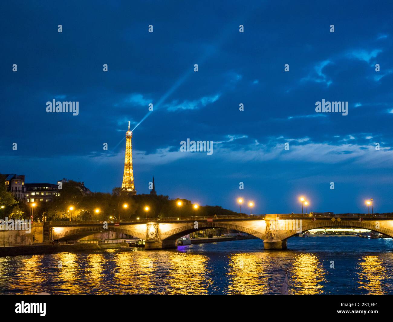 Paris, France - 19 April 2022: Illuminated Eiffel tower and Pont des Invalides, seen from the river Seine at night Stock Photo