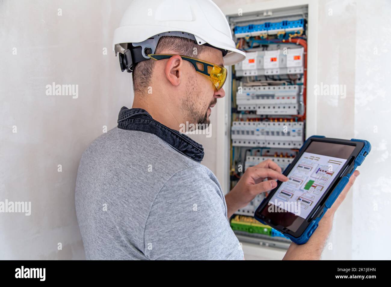 Electrical technician looking focused while working in a switchboard with fuses. Stock Photo