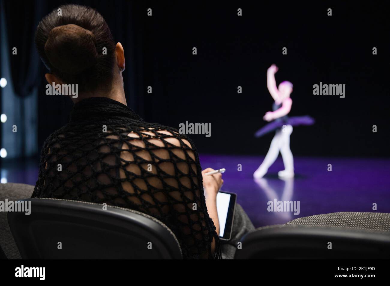 Female director judging ballerina on stage Stock Photo