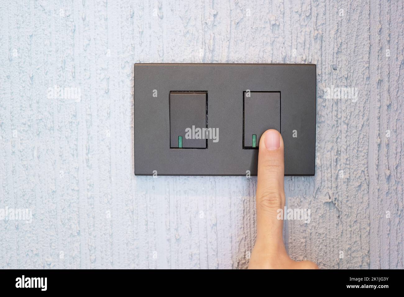Closeup Male finger is turn on or off on light switch on wall at home ...