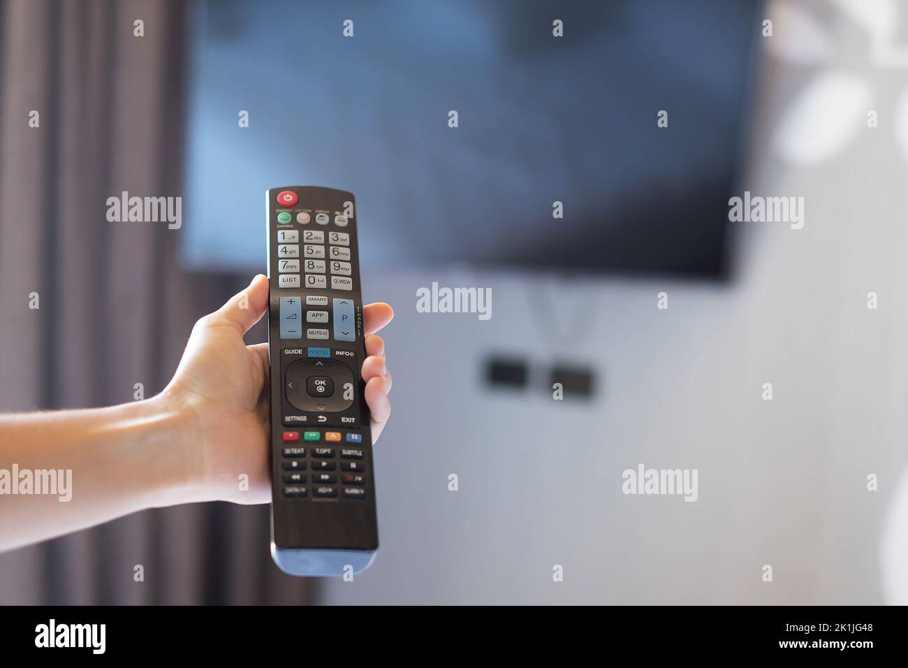 hand using remote controller for adjust Smart TV inside the modern room ...