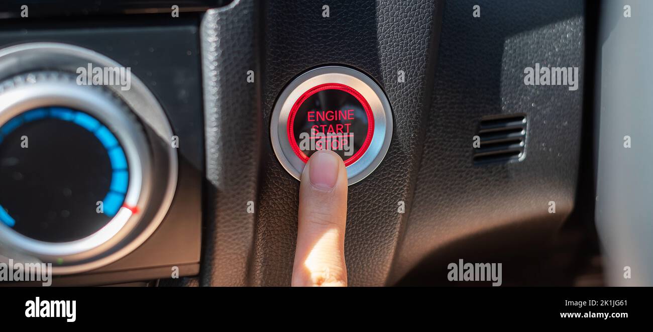 Finger press a car ignition button or START engine inside modern