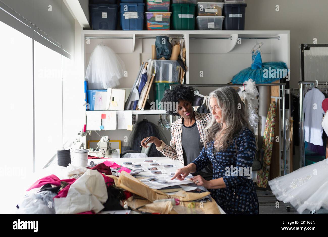 Female fashion designers reviewing photographs in workshop Stock Photo