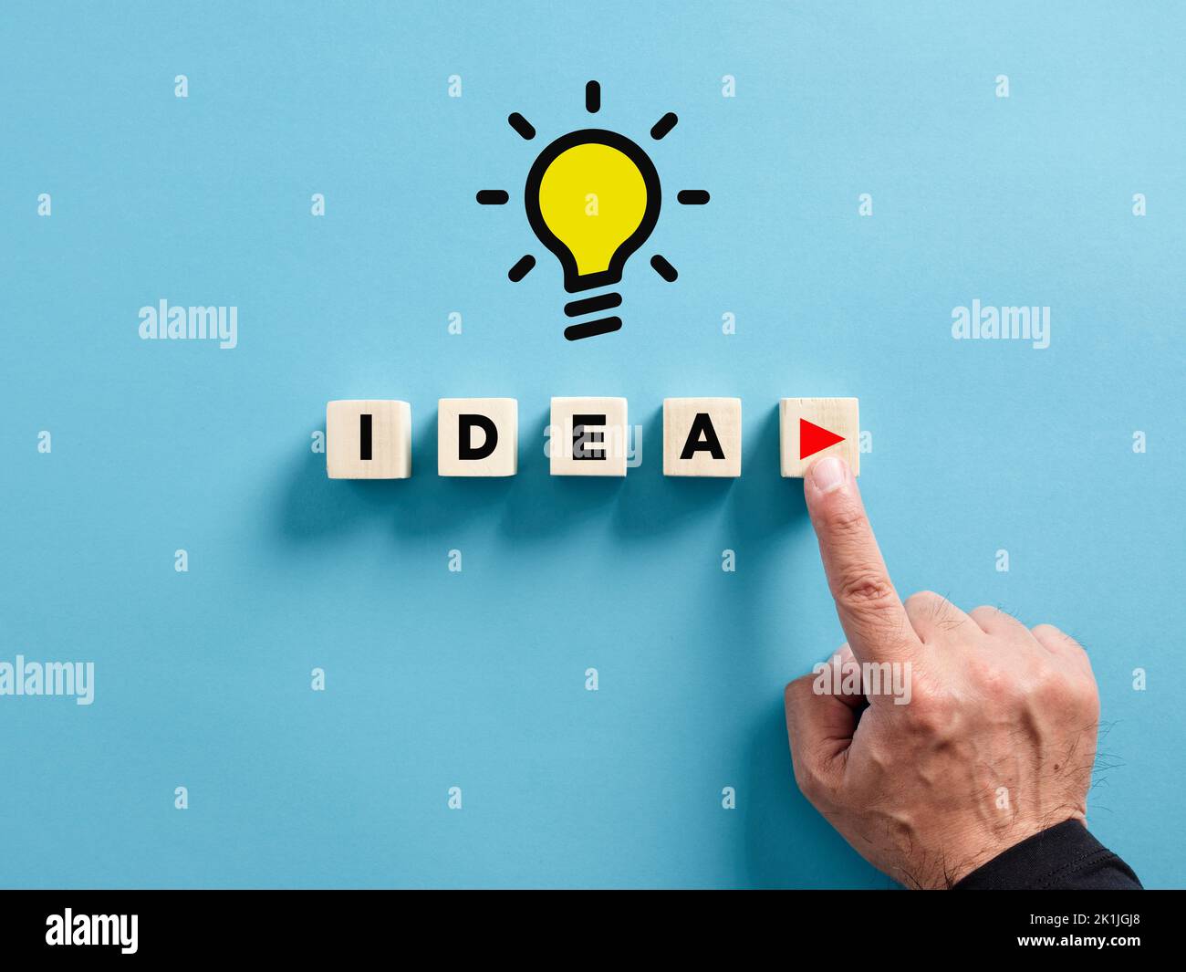 Male hand presses the play button with the word idea on wooden cubes. To execute an idea concept. Stock Photo