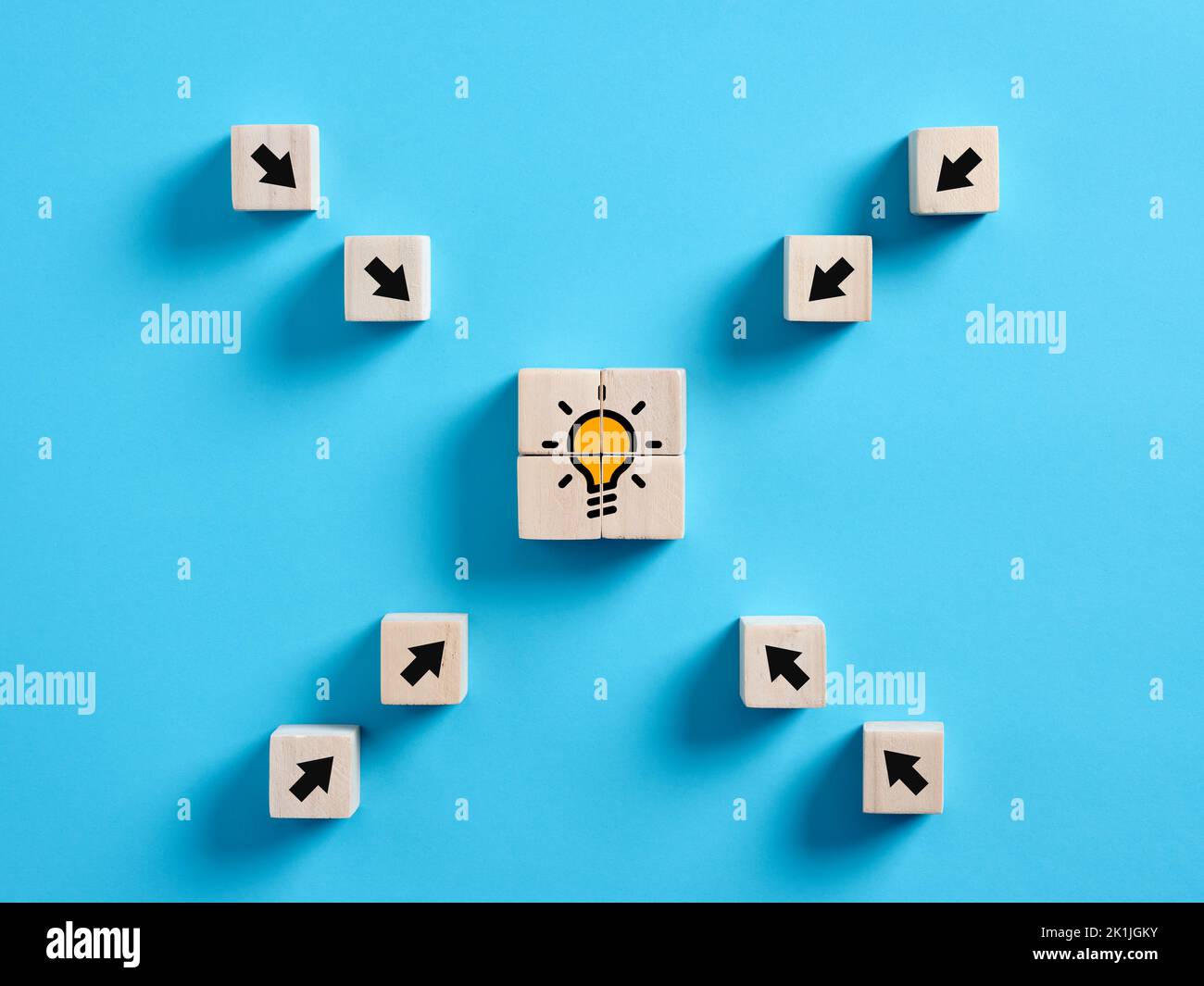 Arrows pointing towards the idea light bulb icon on wooden cube. To find the right idea, to achieve creativity in business or education concept. Stock Photo