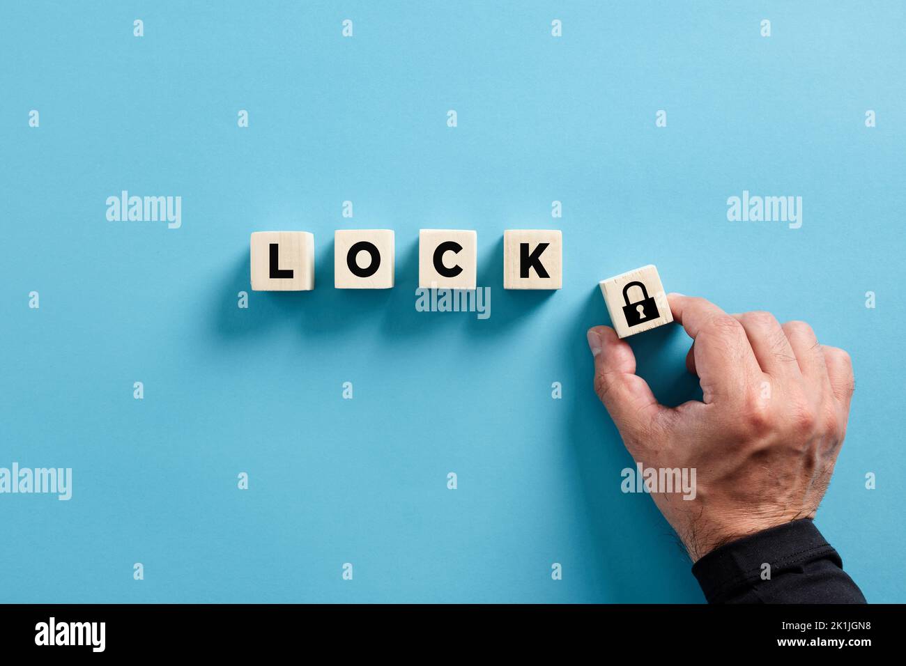Male hand puts the wooden cube with padlock icon with the word lock. Privacy, security, protection and safety concepts. Stock Photo