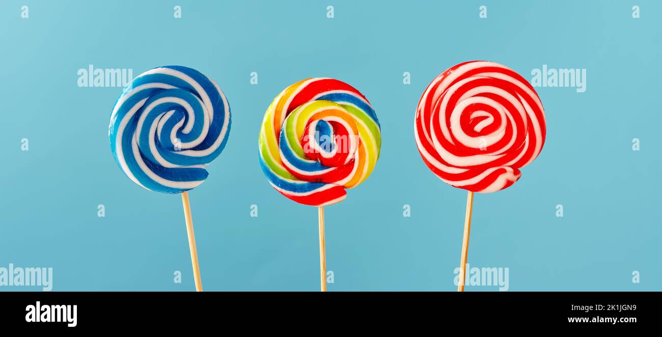 Colorful swirl round candy lollipops on blue background. Stock Photo