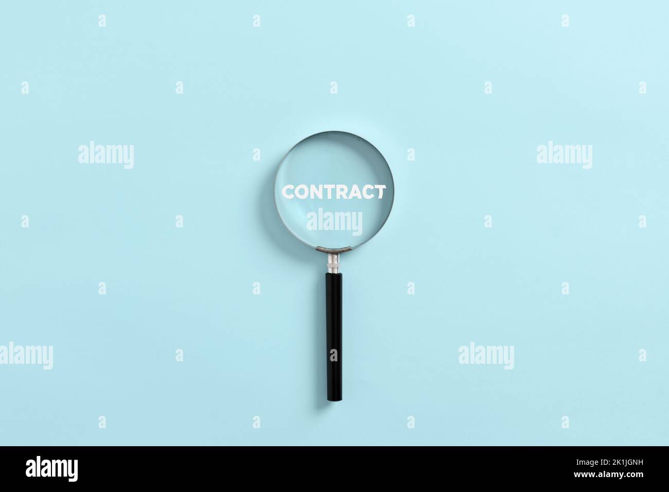 Magnifying glass magnifies the word contract. Analyzing or investigating the business contract concept. Stock Photo
