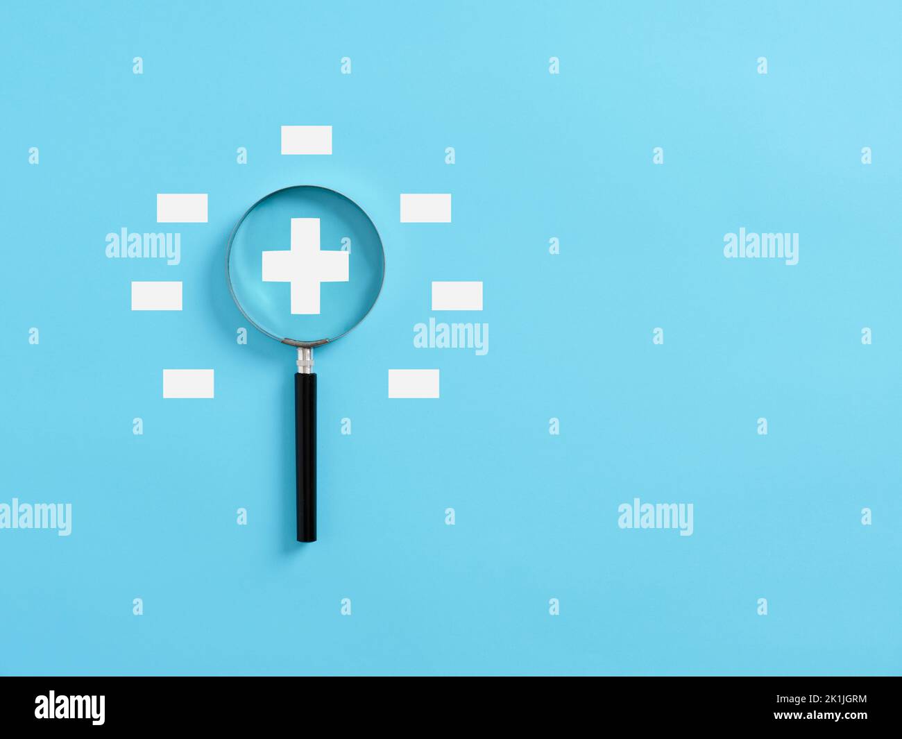 Magnifying glass magnifies the plus symbol surrounded with minus symbols. Focusing on the positive concept. Stock Photo