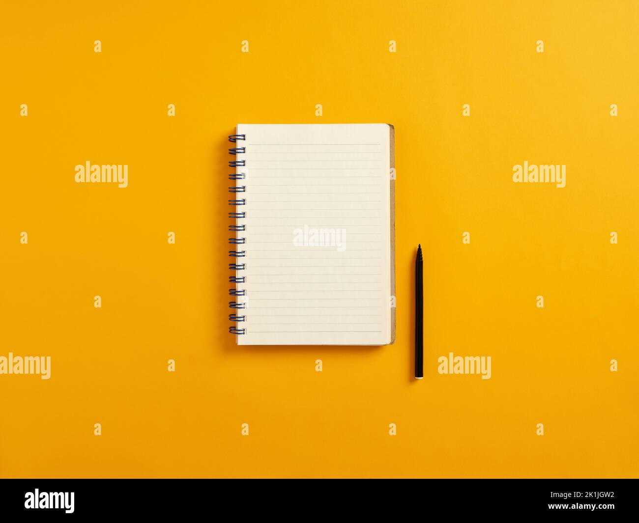 Blank or empty notepad and black pen on yellow background with copy space. Stock Photo