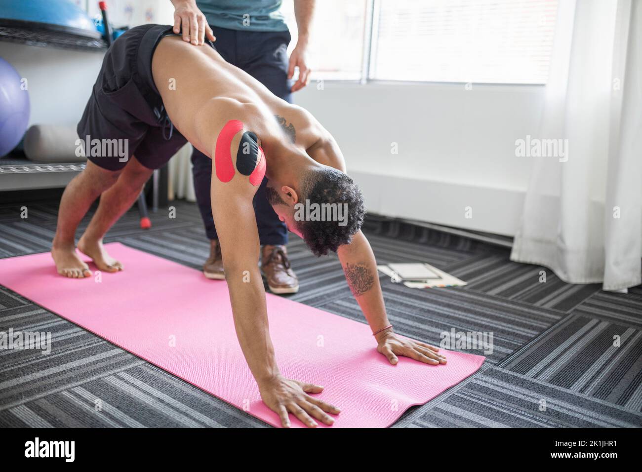 Physiotherapist helping male client in yoga position Stock Photo