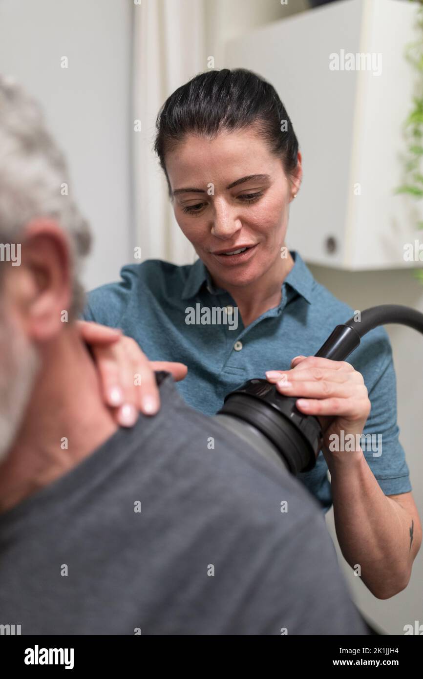 Natural medicine practitioner treating client with shoulder pain Stock