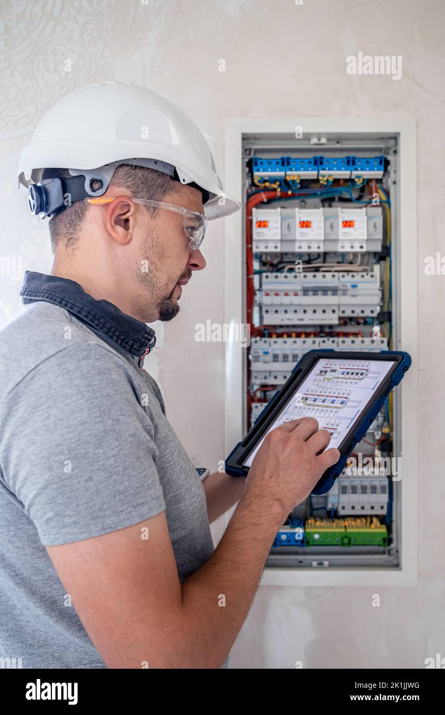 Electrical technician looking focused while working in a switchboard with fuses. Stock Photo