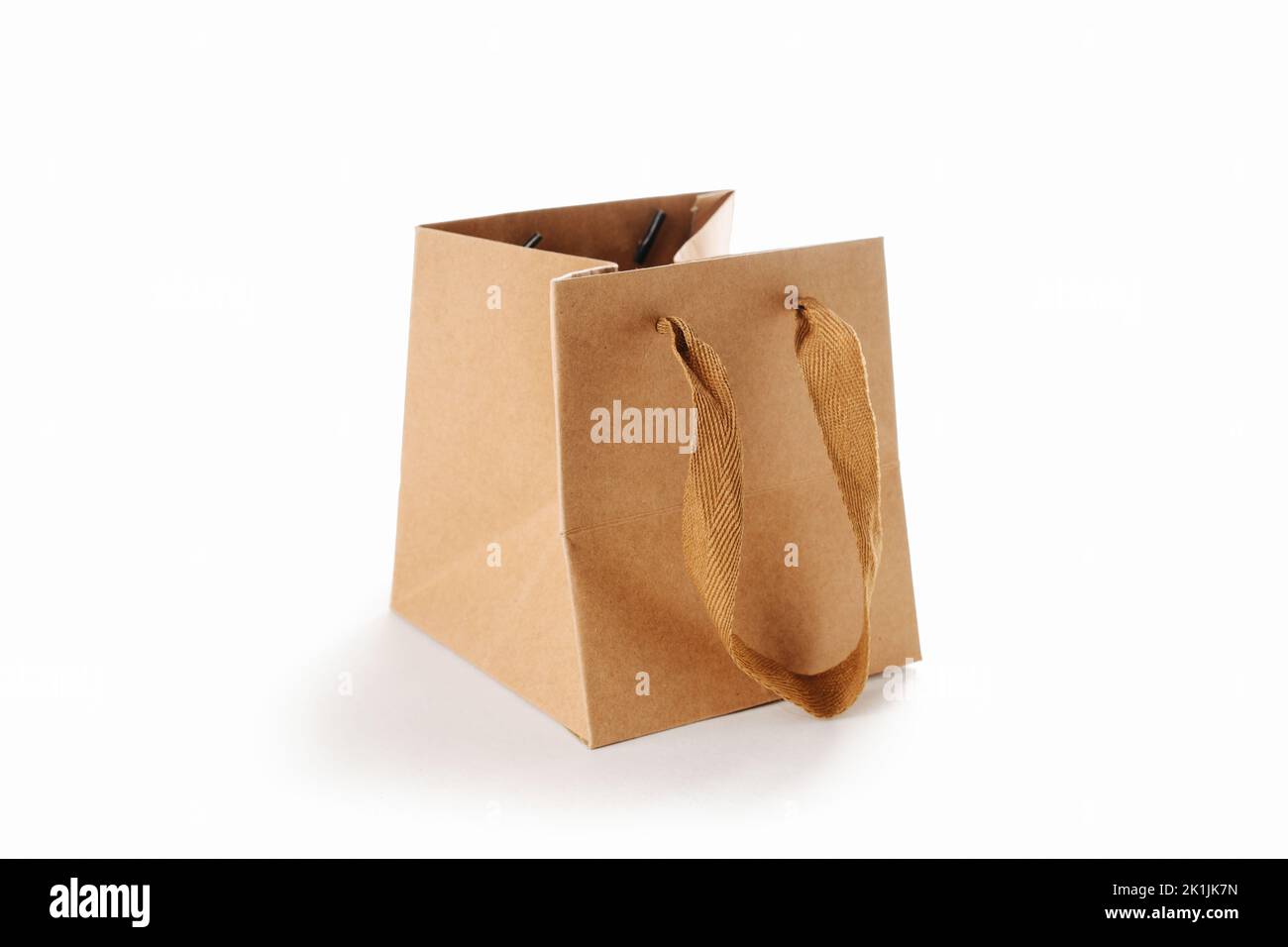 Square paper bag with cloth handles, partially folded. Over white background. Stock Photo