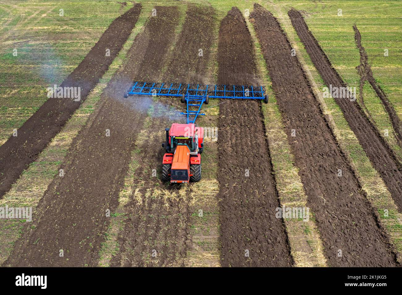 Agriculture machine harvesting crop in fields. Tractor pulls a mechanism for haymaking. Harvesting in autumn in the morning at dawn. agribusiness in t Stock Photo