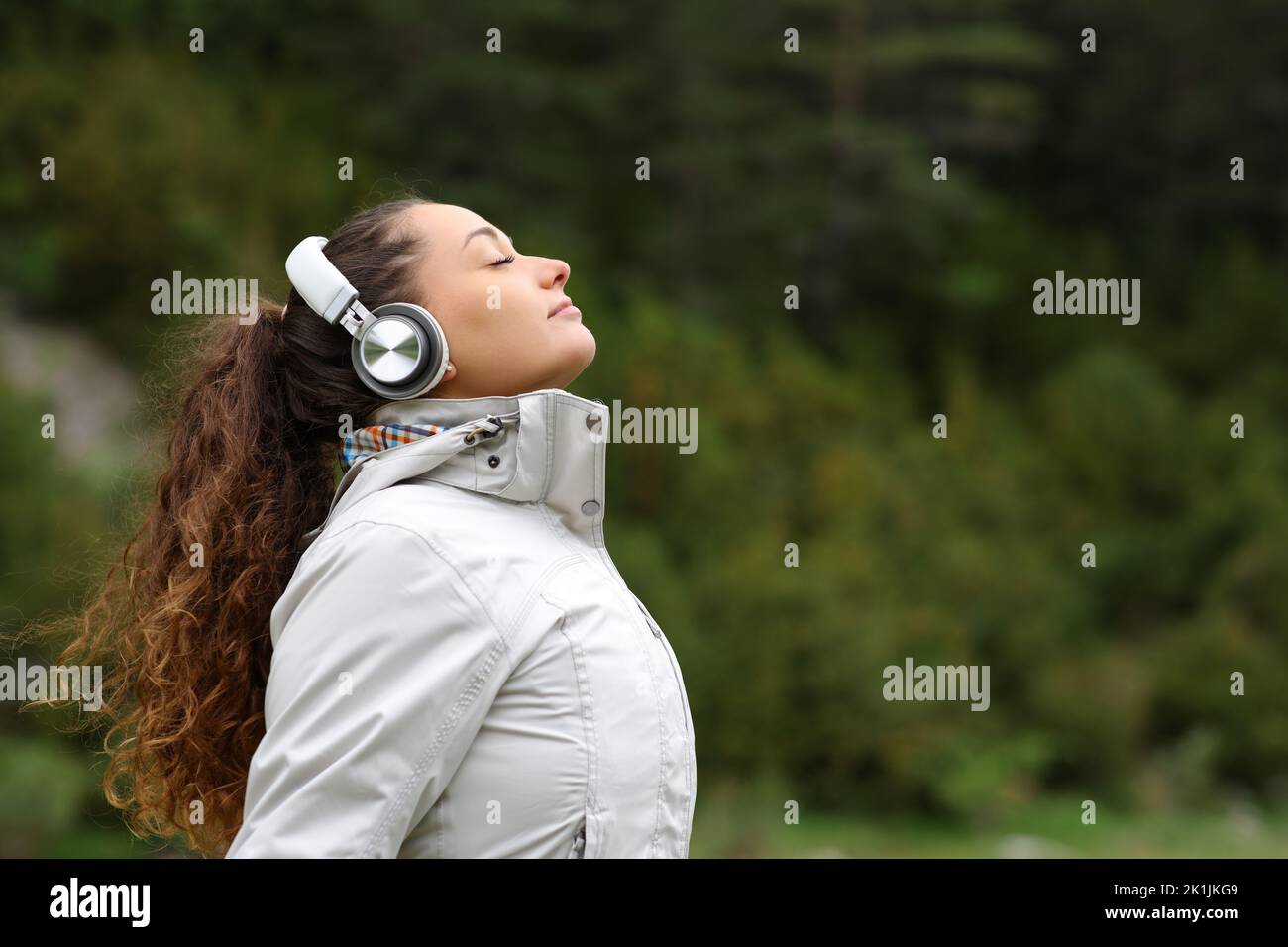 Profile of a hiker with headphones breathing fresh air in the mountain Stock Photo