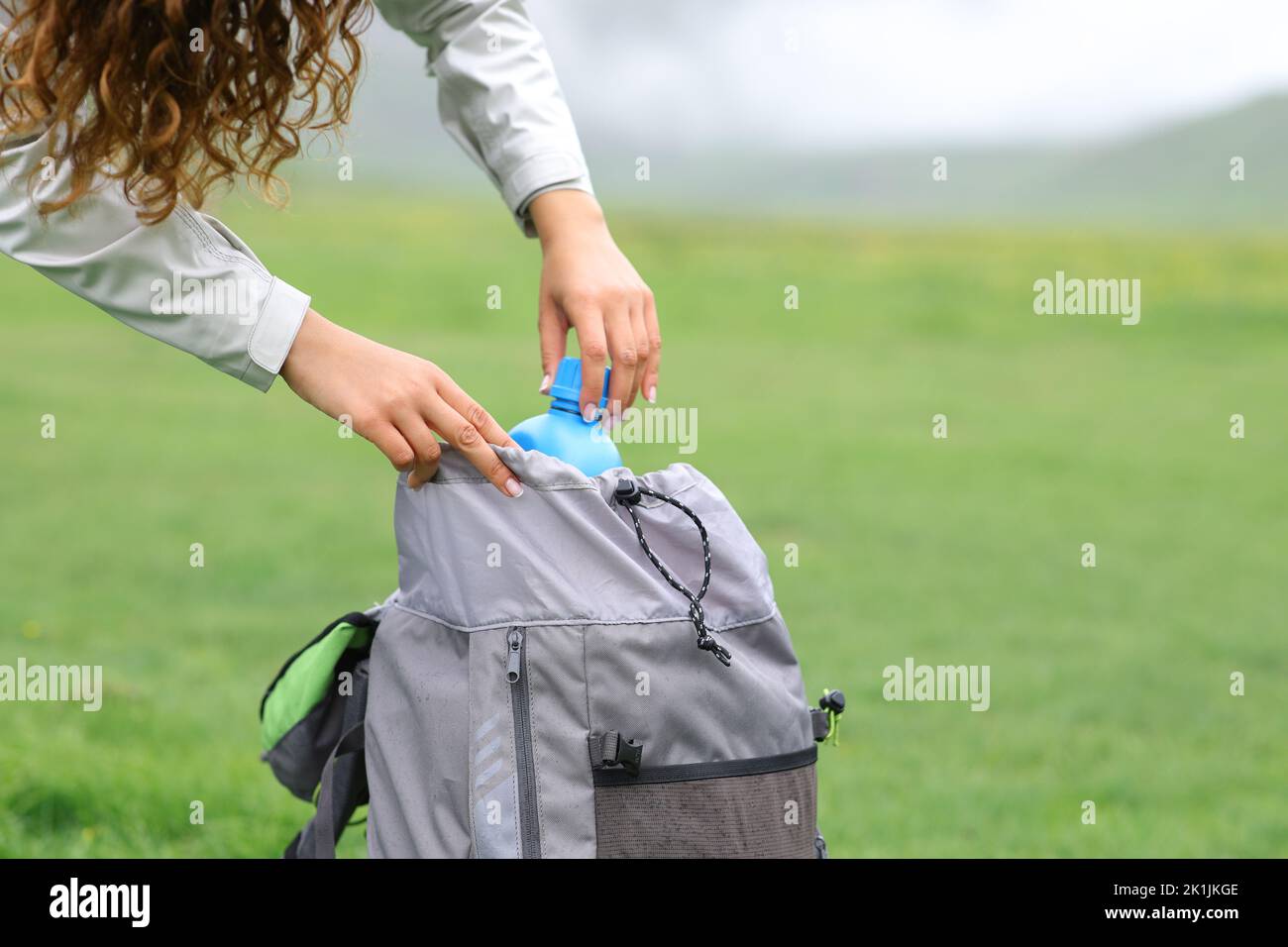 Close up of a hiker hands putting canteen in a backpack Stock Photo